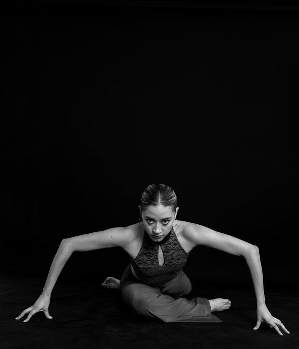 Woman performing a calm, controlled cardio movement in a minimalist dark studio.